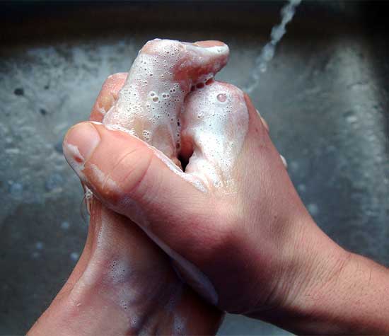 two hands graps while washing them under the faucet