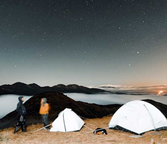 two people talking around two tents in the dark