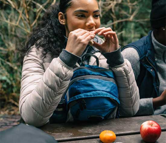 student eating hiking food at picnic table