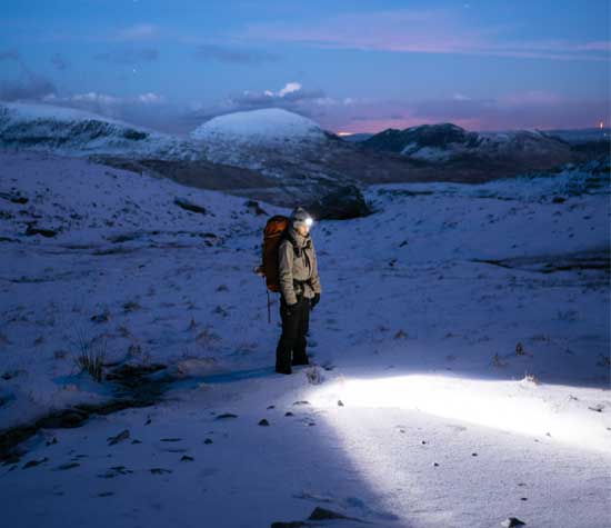 climber with headlight on snowy mountain