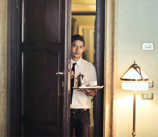 waiter entering hotel room with coffee