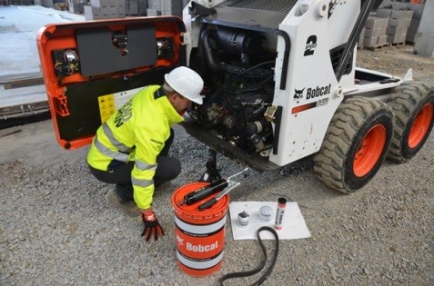 person inspecting skid steer loader/tractor